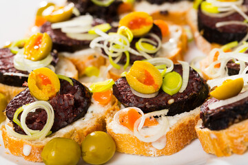 Image of tasty canapes from blood sausage with bread and olives, served at plate