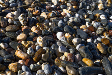 Unique background texture pattern colorful wet pebble stones on the beach.