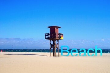 lifeguard tower at a wonderful beach, blue beach lettering with shadow next to it, Atlantic Ocean,...