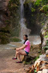 Woman sitting by the waterfall taking a break on an ecotourism trip enjoying the rainforest and tropical climate in Mexico