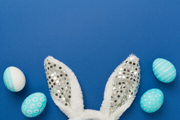Blue easter eggs with bunny on color background, top view