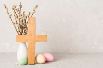 Easter eggs with wooden cross on concrete background