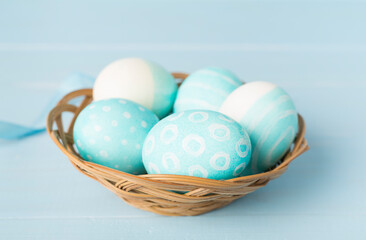 Naklejka na ściany i meble Blue easter eggs in basket on wooden table