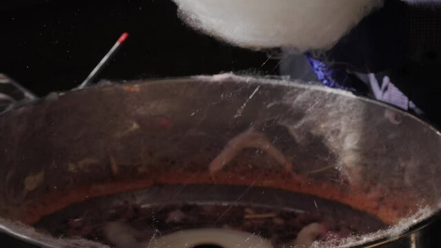 Making cotton candy or candy floss close-up. A spun sugar confection that resembles cotton. Local food festival with street food. 