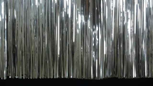 銀色のテープで作られたカーテンの端が波のように揺らめく光の装飾