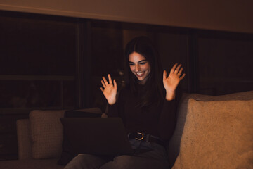 Fototapeta premium Happy caucasian young girl student watch webinar listen online course communicate by conference video call e learn language in app laugh study with teacher lesson look at laptop at night .