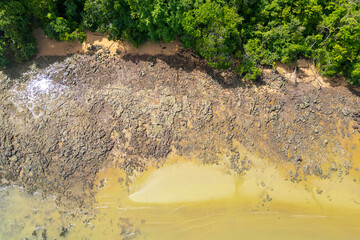 Aerial drone view of a freshwater beach, harmonizing the textures of water, sand, rocks, and lush...