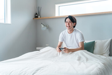 Obraz premium 家のベッドルーム・寝室でゲームをする男性ゲーマー（不摂生・遊ぶ・ストレス解消） 