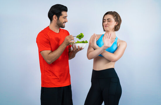 Full body length gaiety shot athletic and sporty young couple with healthy vegan food in standing posture on isolated background. Healthy active and body care by vegetarian lifestyle.