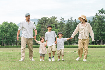 夏休みに公園を手を繋いで歩く家族・ファミリー（レジャー・アウトドア・ピクニック・キャンプ・思い出）
 - obrazy, fototapety, plakaty