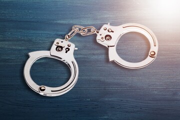A pair of steel handcuffs on desk surface