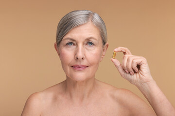 Obraz na płótnie Canvas Beautiful woman with vitamin capsule on beige background