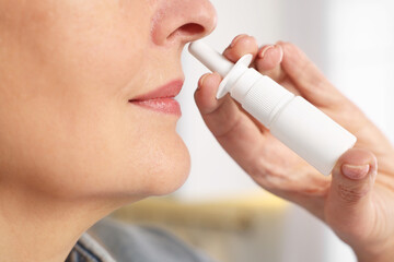 Medical drops. Woman using nasal spray indoors, closeup