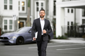 Businessman walking in city. Gray hair business man walk on city street. Business man walking outdoor, hold laptop. Business man in suit go to office work. Successful business.