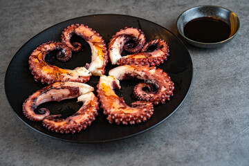 Fried octopus tentacles on a black plate. 