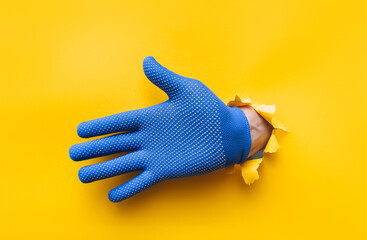 The right male hand in a blue fabric work glove shows an open palm saying hello. Torn hole in...