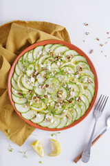Cucumber Salad with White Cheese and Nuts Ingredients on a wooden chopping board and white background