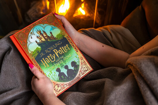 Teenage girl reading the first book about Harry Potter near the fireplace. "Harry Potter and the Philosopher's Stone"