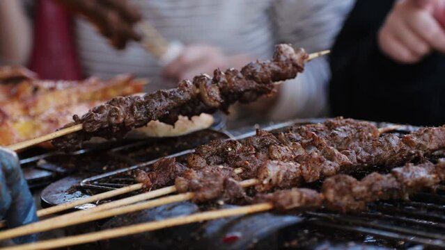 Pork meat skewer on fire, Mutton barbecue close-up. Fried meat for kebab. Cooking grilled meat beef chicken lamb BBQ . Kebab on grill. Chinese street local market with traditional food