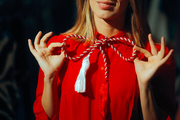 Detail of a Red and White Martisor Accessory Bow. Hands tie a bow from a beautiful traditional...
