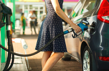 Woman fills petrol into her car - obrazy, fototapety, plakaty