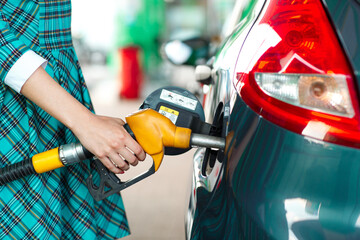 Woman fills petrol into her car at a gas station - obrazy, fototapety, plakaty