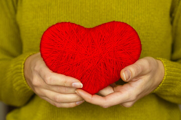 Closeup on red heart made from wool in hand of woman
