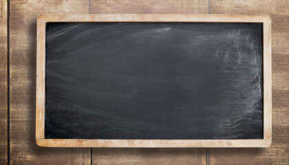 Empty blank black chalkboard with chalk traces; old wooden table surface background