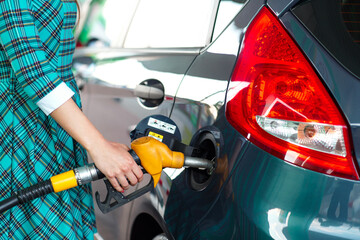 Woman fills petrol into the car at a gas station