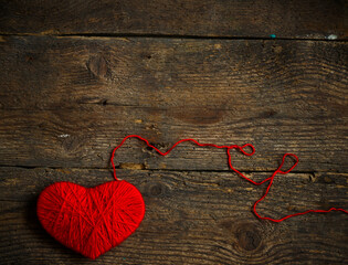 Red heart shape made from wool on old shabby wooden background
