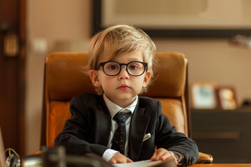  Young business boy child a little boss in office boring job
