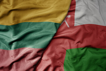 big waving national colorful flag of oman and national flag of lithuania .