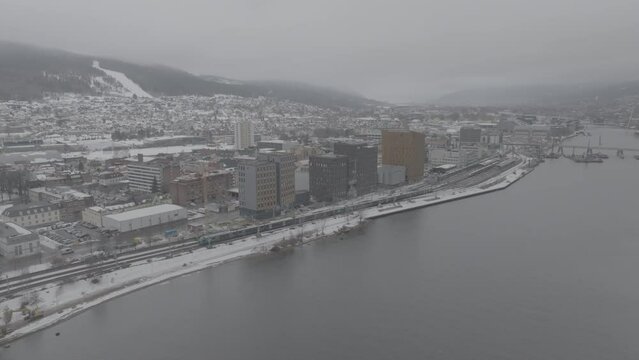 Drone video of Drammen city in Norway during winter. River and railway on a cloudy day.