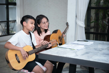 Mother and son playing guitar together Practice looking at music notes. Use music to create...