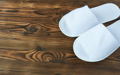 White slippers on wooden background. Top view with space for copying. Slippers for a hotel.