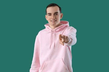 Young man pointing at viewer on green background