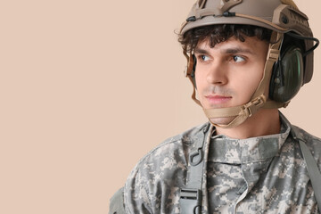 Young male soldier on beige background, closeup