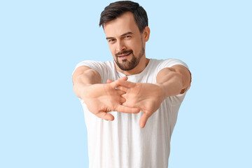 Handsome man stretching on blue background