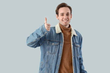 Young man showing thumb-up on light background