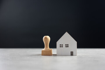 Rubber stamp and model home on table with black background, approved application contract, bank approved, personal loan, home loan approved, loan application