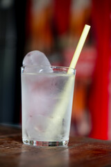Water glass with ice and straw in the glass on the table