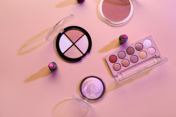 Beautiful palettes of eyeshadows and different decorative cosmetics on pink background - obrazy, fototapety, plakaty