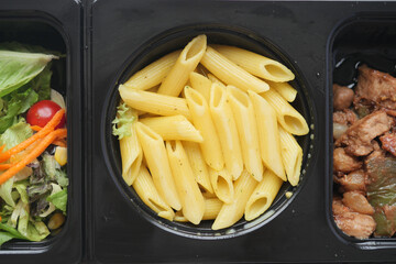 a close up of a bowl of pasta next to a bowl of salad and a bowl of meat