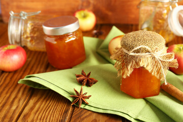 Jars of sweet apple jam with star anise and cinnamon on wooden background