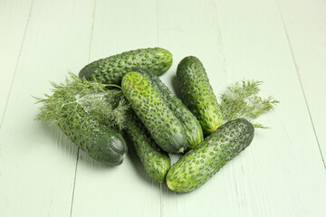 Heap of fresh cucumbers with dill on green wooden background