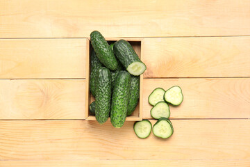 Box with fresh cucumbers on wooden background