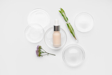 Petri dishes with herbs and bottle of cosmetic product on white background