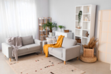Blurred view of modern living room with grey sofas