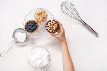 Female confectioner with tasty cakes on white background
