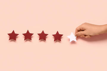 Female hand with four out of five stars rating on pink background. Customer experience concept